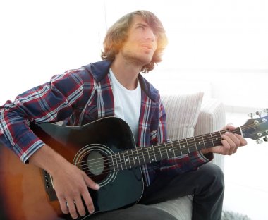 modern adam kanepede oturan gitar çalmak. bir yaşam tarzı kavramı