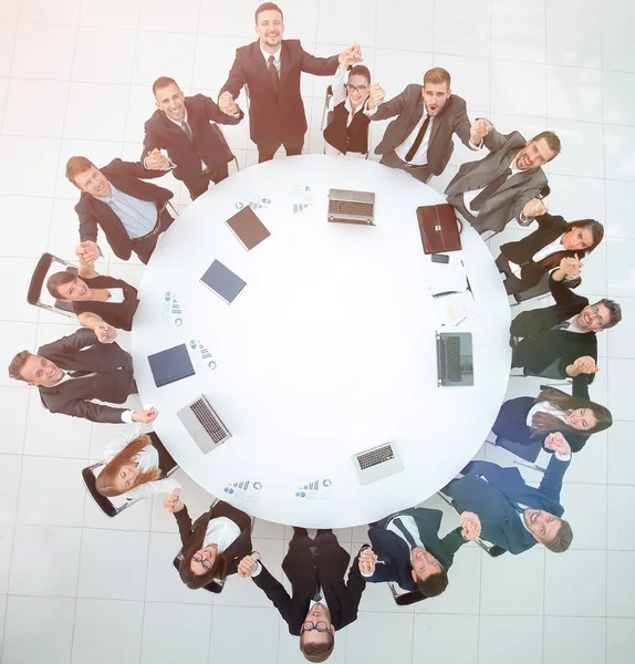 Μεγάλη επιχειρηματική ομάδα κάθεται στη στρογγυλή τράπεζα και σηκώνει τα χέρια ψηλά — Φωτογραφία Αρχείου