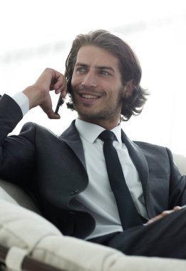 iş adamı rahat bir sandalyede otururken Smartphone'da konuşuyor.