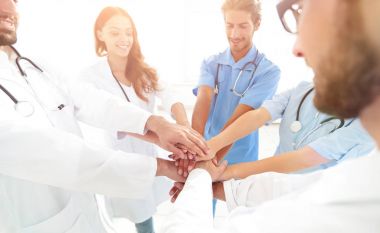 Doktorlar ve hemşireler tıbbi bir ekipte el ele tutuşuyorlar.