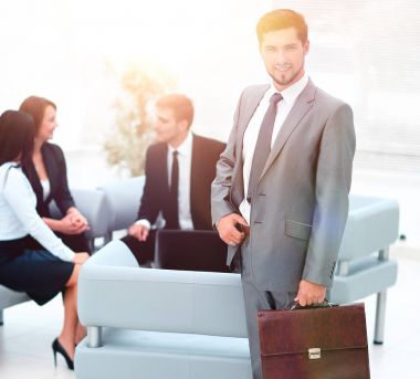 Evrak Çantası'nı ayakta ofisinin lobisinde ile kendine güvenen iş adamı.