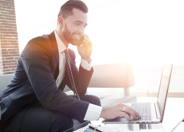 Empresario hablando por teléfono inteligente y escribiendo texto en el portátil —  Fotos de Stock