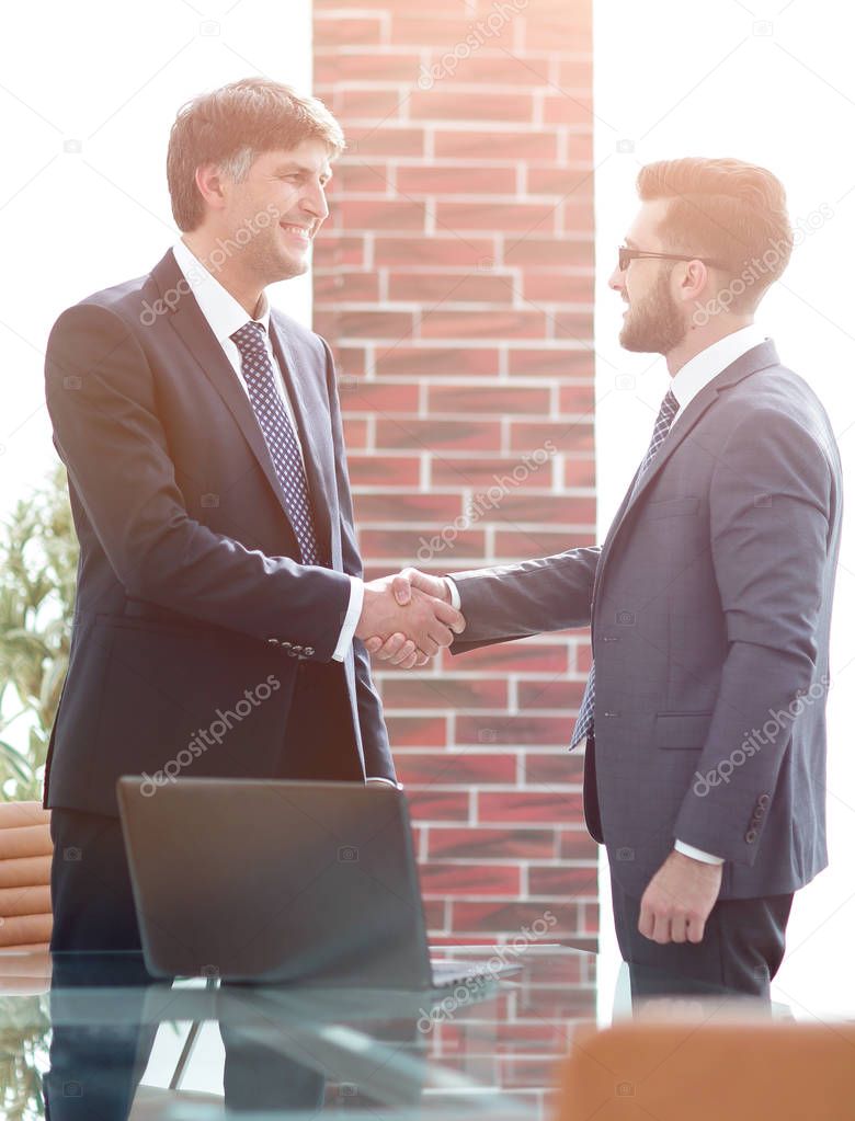 businessmen shaking hands while standing in office corridor