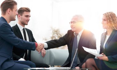 Ortaklar, takım üyelerinin huzurunda anlaşma yapıp el sıkışıyorlar.