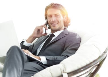 onun evinde sandalyede oturan smartphone cep telefonu ile konuşurken işadamı