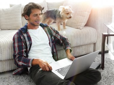 mutlu genç adam köpeğiyle oturma odasında exults