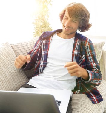 dizüstü bilgisayar ekranına bakarak mutlu genç adam