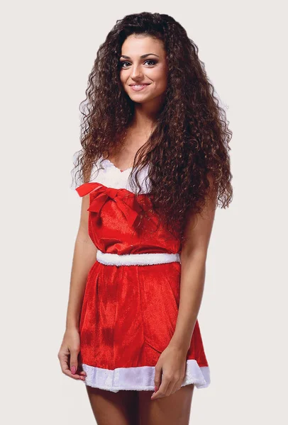 Foto de uma morena atraente em um vestido de Papai Noel . — Fotografia de Stock