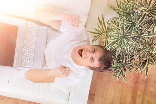 Homme à succès avec les bras levés travaillant sur ordinateur portable à la maison — Photo