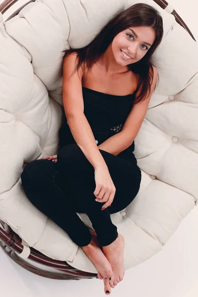 Usměvavá mladá žena odpočívá ve velké měkké křeslo — Stock fotografie