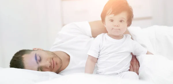 Un bambino è seduto sul letto a casa con suo padre — Foto Stock