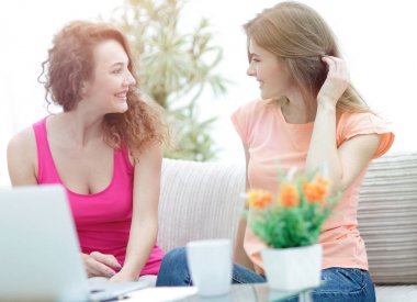 İki genç kadın kahve masasında konuşuyor ve oturuyor.