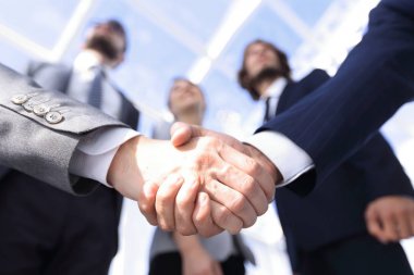 İş ortaklarının el sıkışması ön planda.