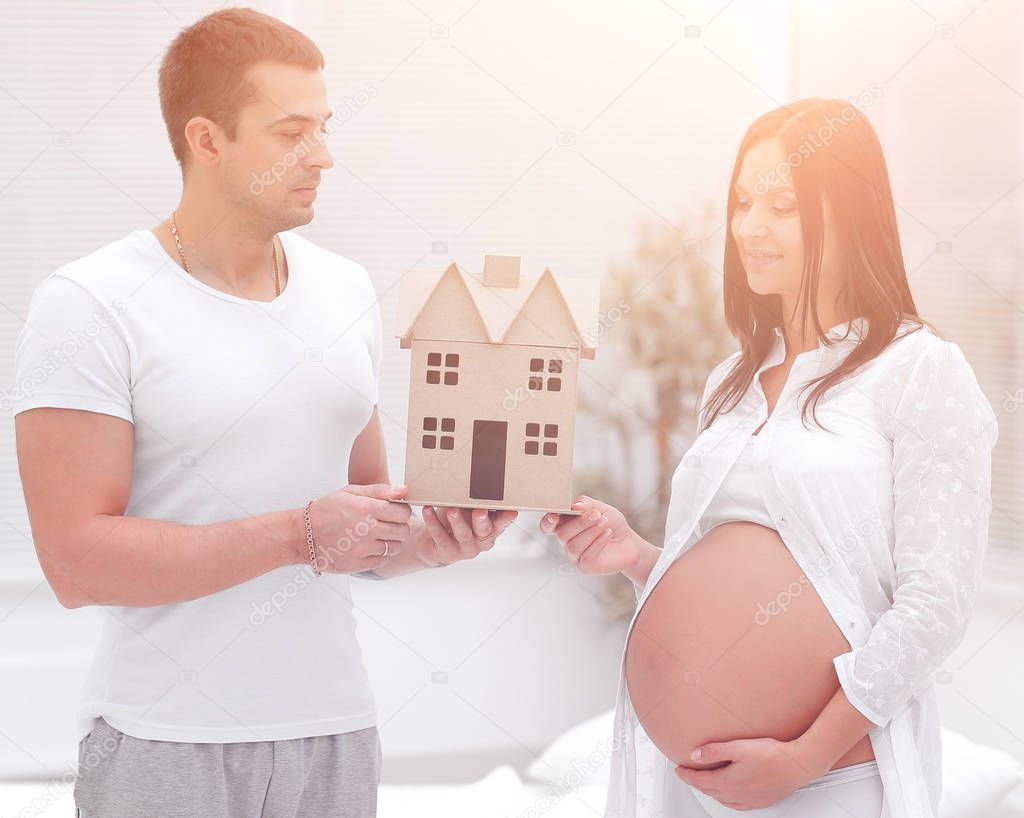 husband showing his pregnant wife a layout of their future home.