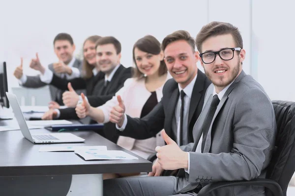 Equipo de negocios con los pulgares hacia arriba mientras está sentado en su escritorio —  Fotos de Stock