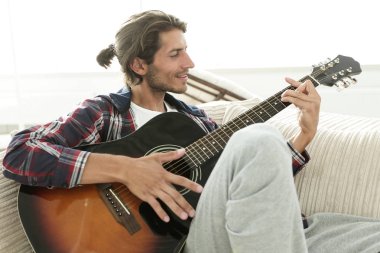 oturma odasında kanepede oturup gitar ile Modern adam.