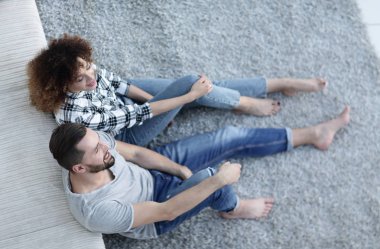 yeni bir oturma odasında bir halı üzerinde oturan yeni evli çift