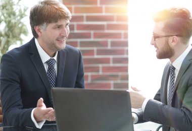 Ofiste bir dizüstü bilgisayar üzerinde çalışan iki iş adamları