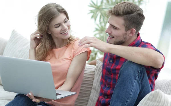 Jonge man en zijn vriendin kijken naar foto's op de laptop. — Stockfoto