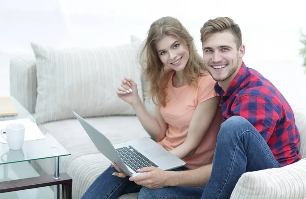 Pair students with a laptop sitting on sofa — Stock Photo, Image