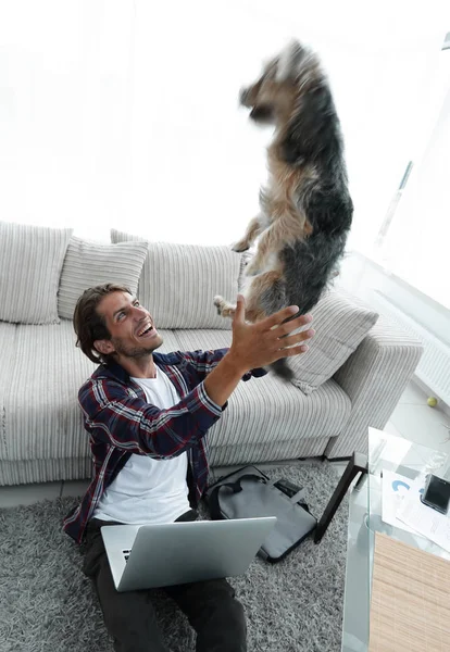 Giovane uomo moderno che gioca con il suo cane in un ampio soggiorno — Foto Stock