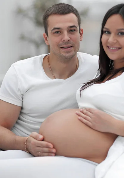 Retrato de la mujer embarazada con el marido sentado en el sofá — Foto de Stock