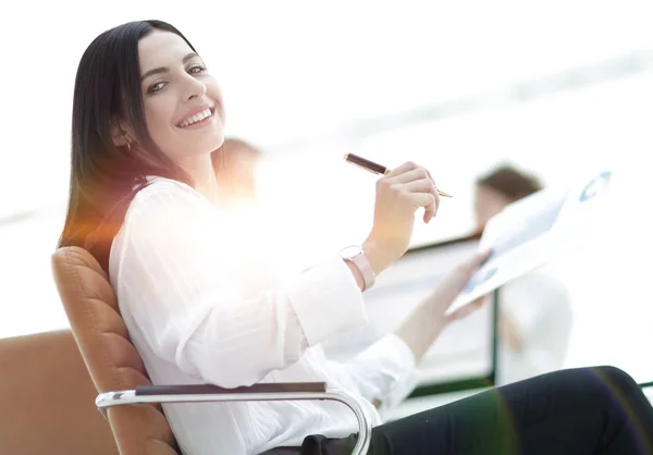 Leende affärskvinna med finansiella dokument sitter vid skrivbord. — Stockfoto