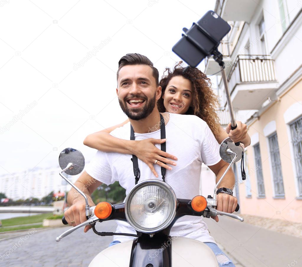 Happy couple on scooter making selfie on smartphone outdoor