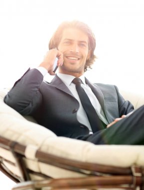 iş adamı rahat bir sandalyede otururken Smartphone'da konuşuyor.