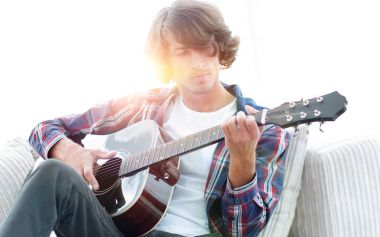 Yakışıklı adam evde kanepede gitar çalmaya