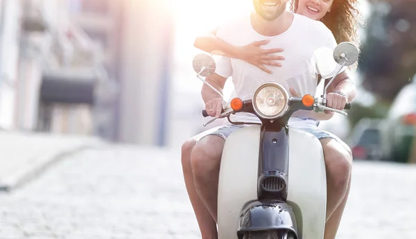 Happy young couple riding a scooter in the city on a sunny day — Stock Photo, Image