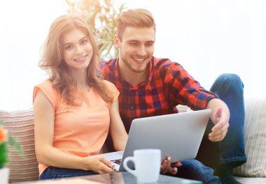 Genç çift çalisarak koltukta oturan laptop