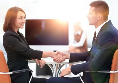 Pazarlık masasında el sıkışan iş ortakları.