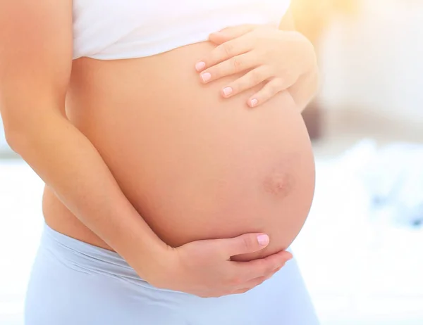 Porträt einer jungen Schwangeren auf hellem Hintergrund. — Stockfoto