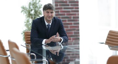 Bir boş konferans salonunda bir masada oturan proje yöneticisi