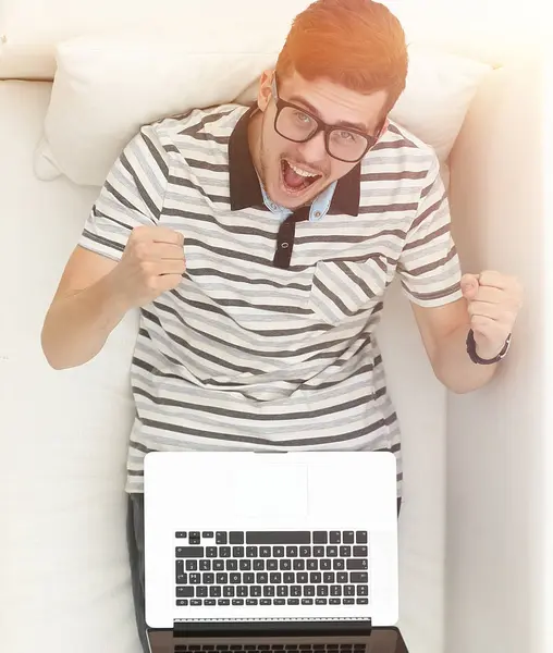 Homem moderno feliz olha para o laptop sentado no sofá . — Fotografia de Stock