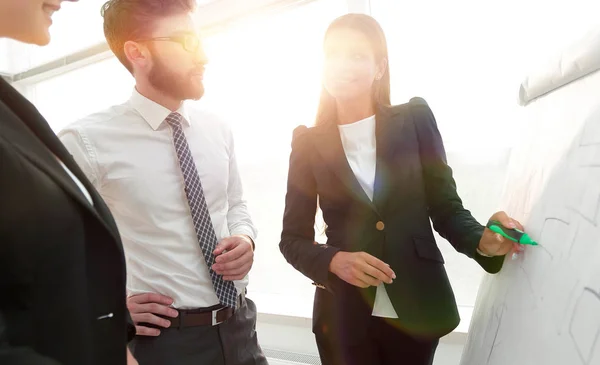 Zakenvrouw aanwijsapparaat horizontale liniaal naar de flipboard op presentatie in office — Stockfoto