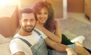 Genç bir çift yeni bir dairede yerde oturuyor.