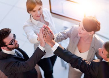 Başarılı bir iş ekibi ofiste birbirlerine beşlik çakıyor.