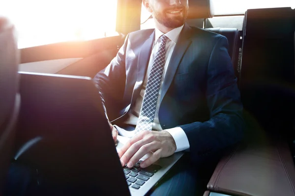 Hombre con portátil sentado en el asiento trasero en el coche — Foto de Stock