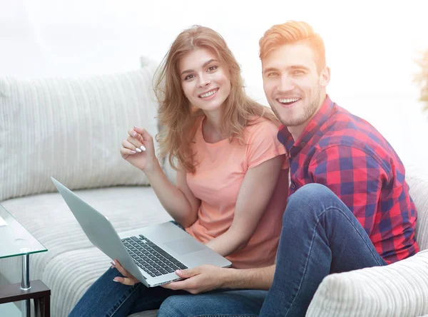 Pair students with a laptop sitting on sofa — Stock Photo, Image