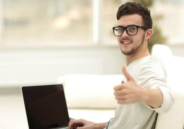 açık belgili tanımlık laptop önünde oturan ve gösterilen modern genç yukarı başparmak