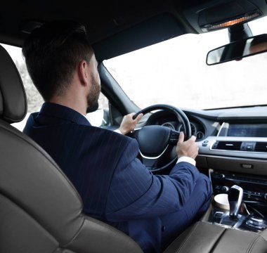 işadamı direksiyonda arabasında oturur ve yola görünüyor