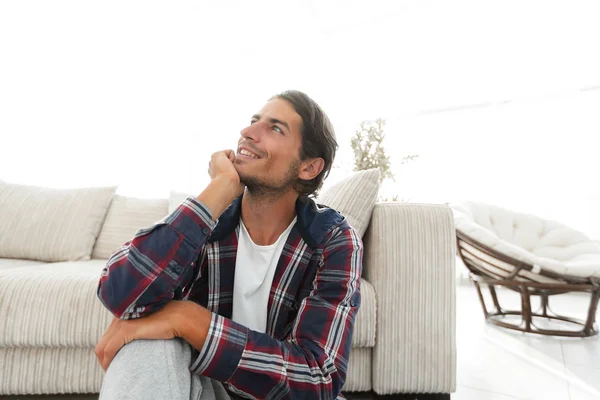 Close-up of a happy guy sitting on the carpet in a new apartment. — Stock Photo, Image