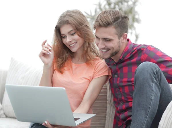 Giovane uomo con la sua ragazza guardando uno spettacolo televisivo sul computer portatile seduto in soggiorno — Foto Stock