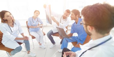 radyologlar ve cerrah hastanın bir grafisi tartışıyor