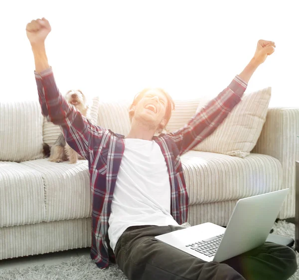 Feliz joven se regocija con su perro sentado en la sala de estar — Foto de Stock