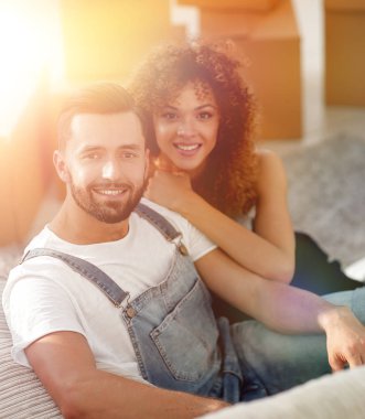 Genç bir çift yeni bir dairede yerde oturuyor.