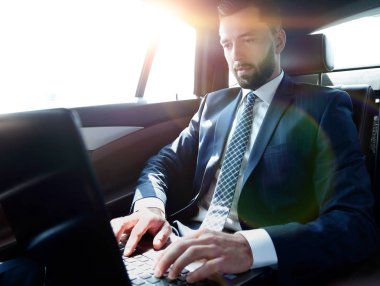 bir arabanın arka koltuğunda oturan işadamı onun laptop kullanma