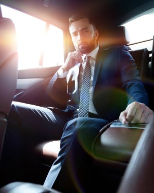 Bir arabanın arka koltuğunda oturan başarılı iş adamı